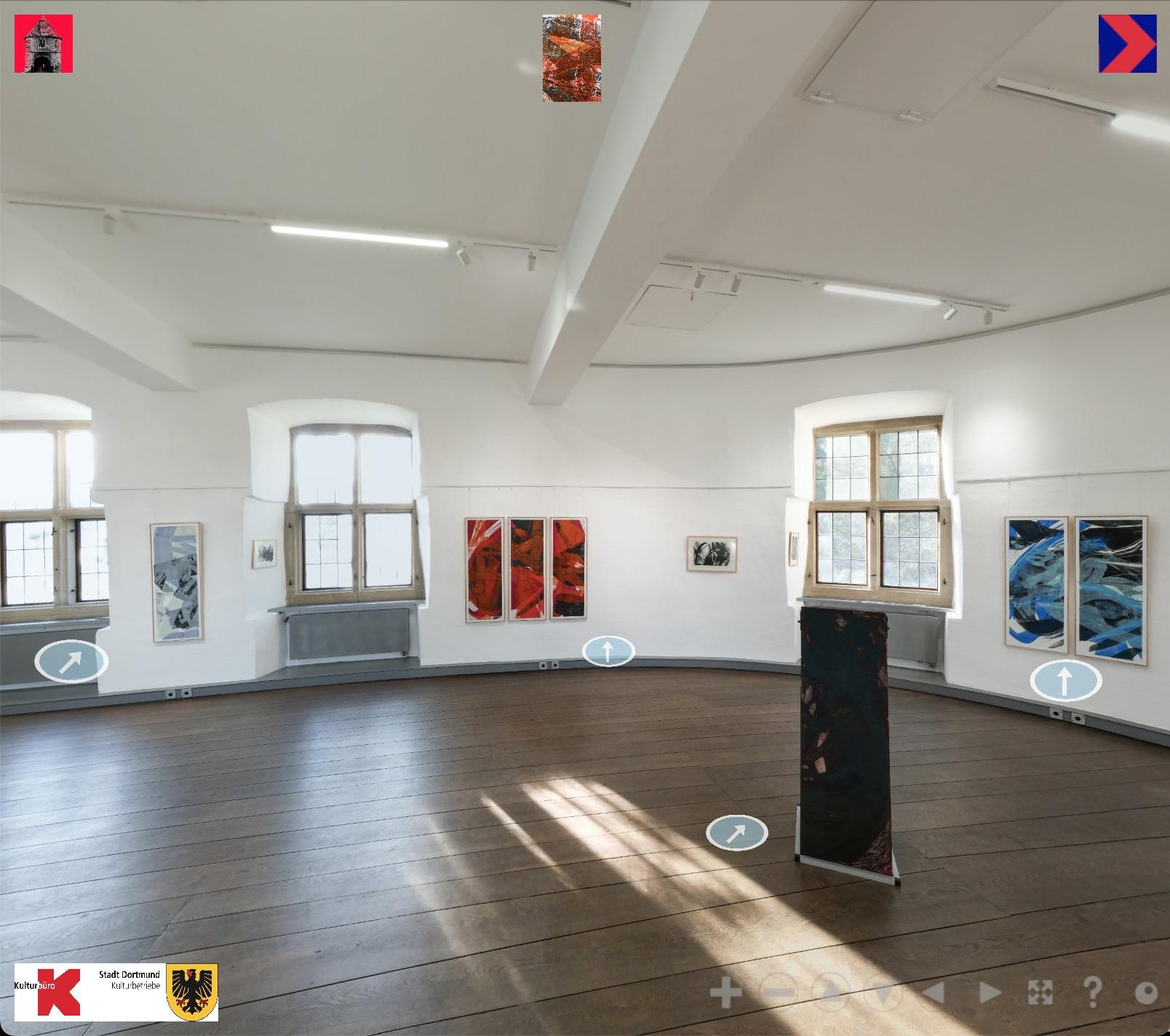 A room with curved, white walls in which medieval windows are set. Green foliage can be seen through the windows. The room has a wooden floor made of thick dark brown planks. There are printed pictures hanging at the walls and sculptures standing in the room.